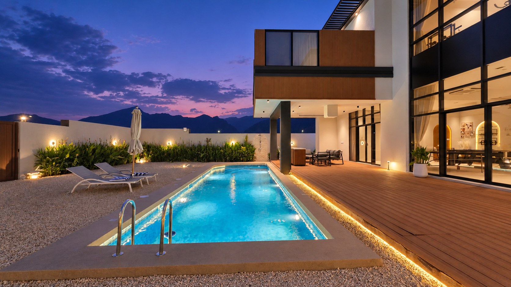 Kenaz Luxury Villa’s illuminated private pool and glass façade at blue hour
