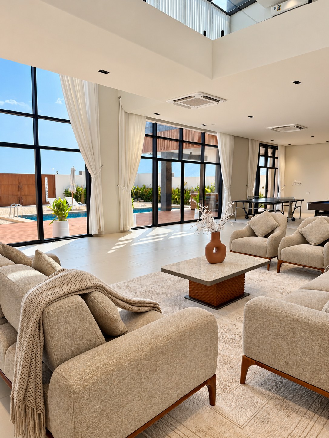 Double-height living room with beige sofas and pool views